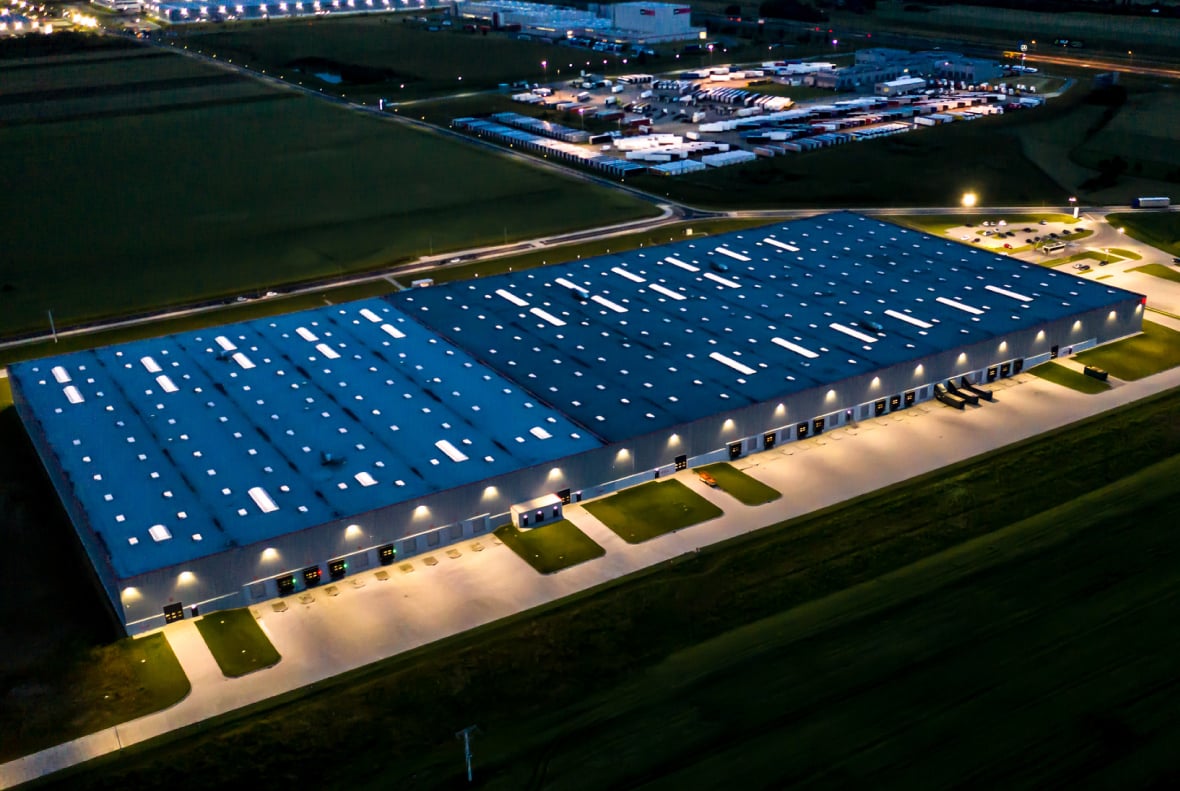 Large warehouse at night, lit up.