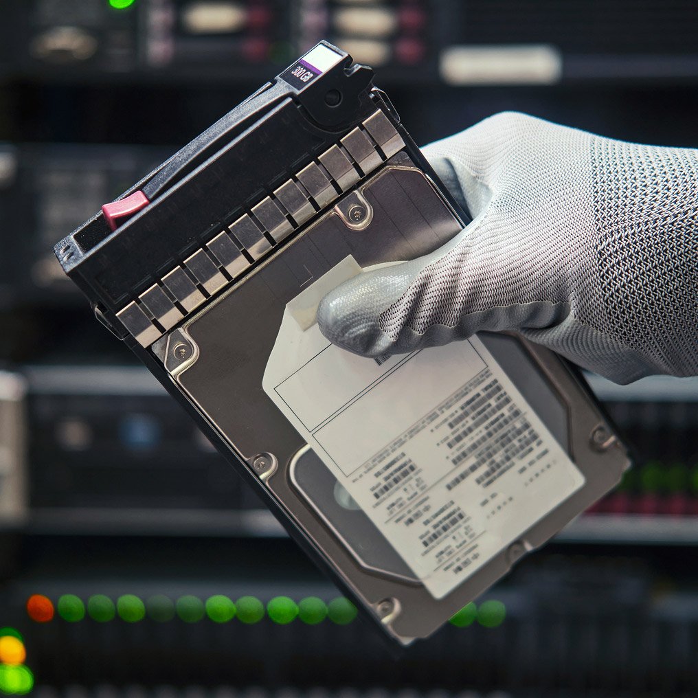 Close-up of a gloved hand holding a hard drive