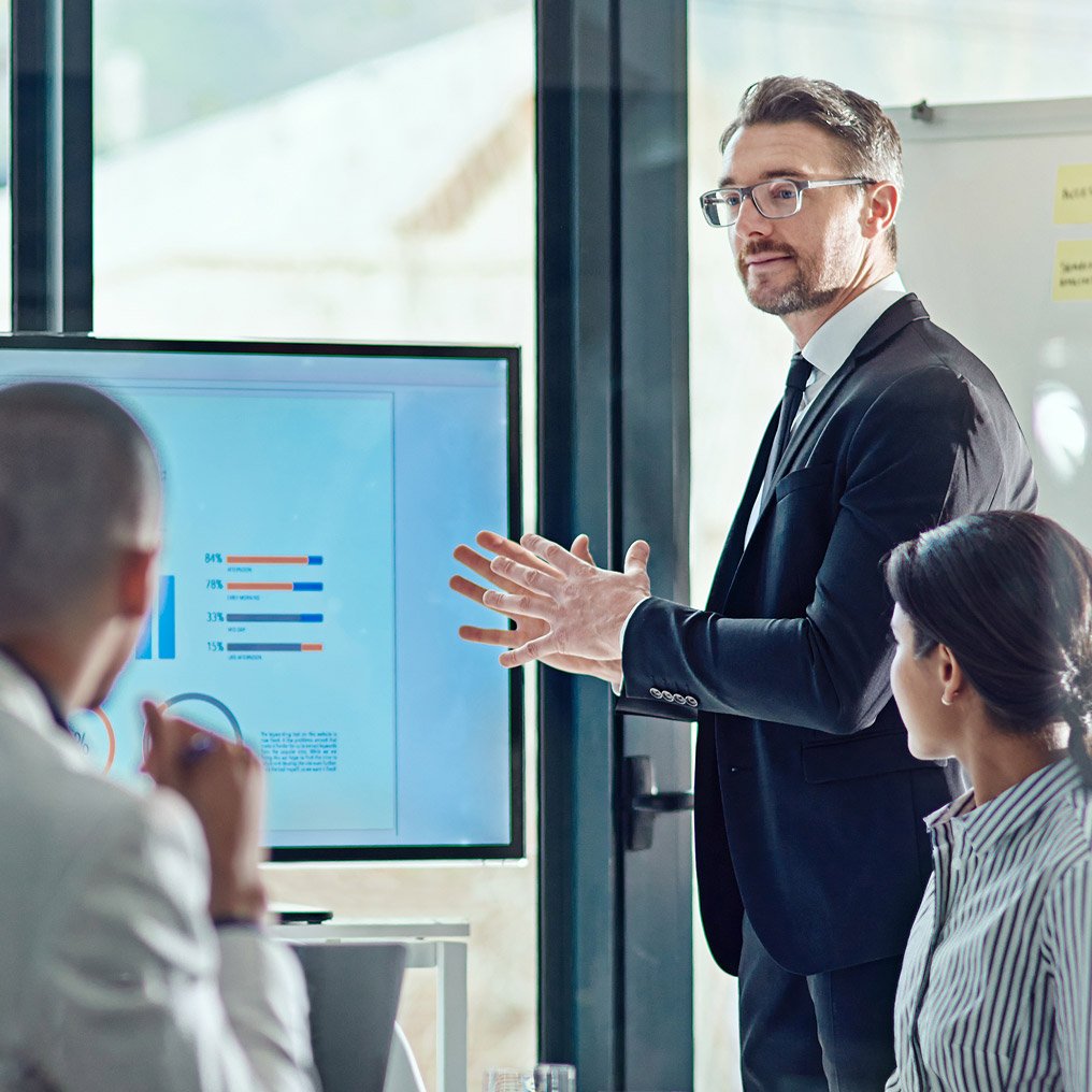 Three people review reports on a screen