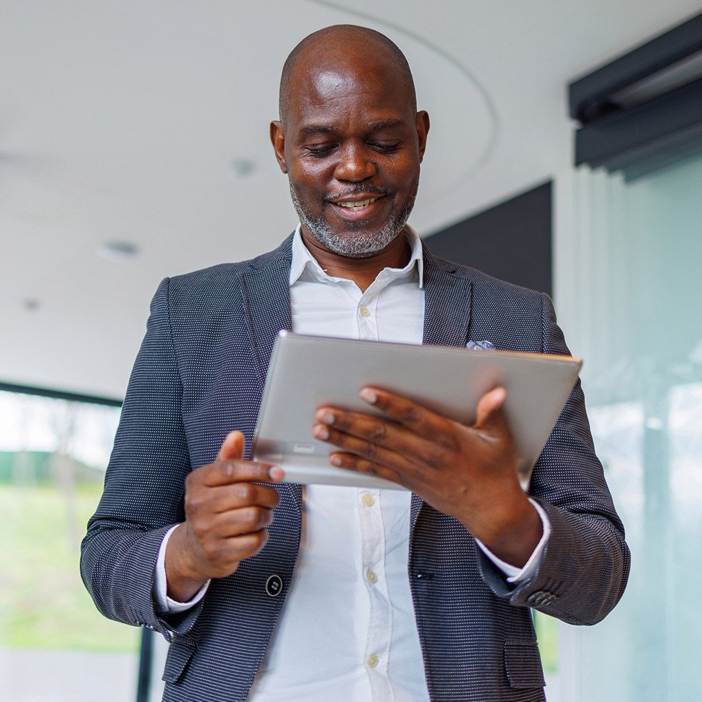 A happy businessman reviews data on his tablet computer