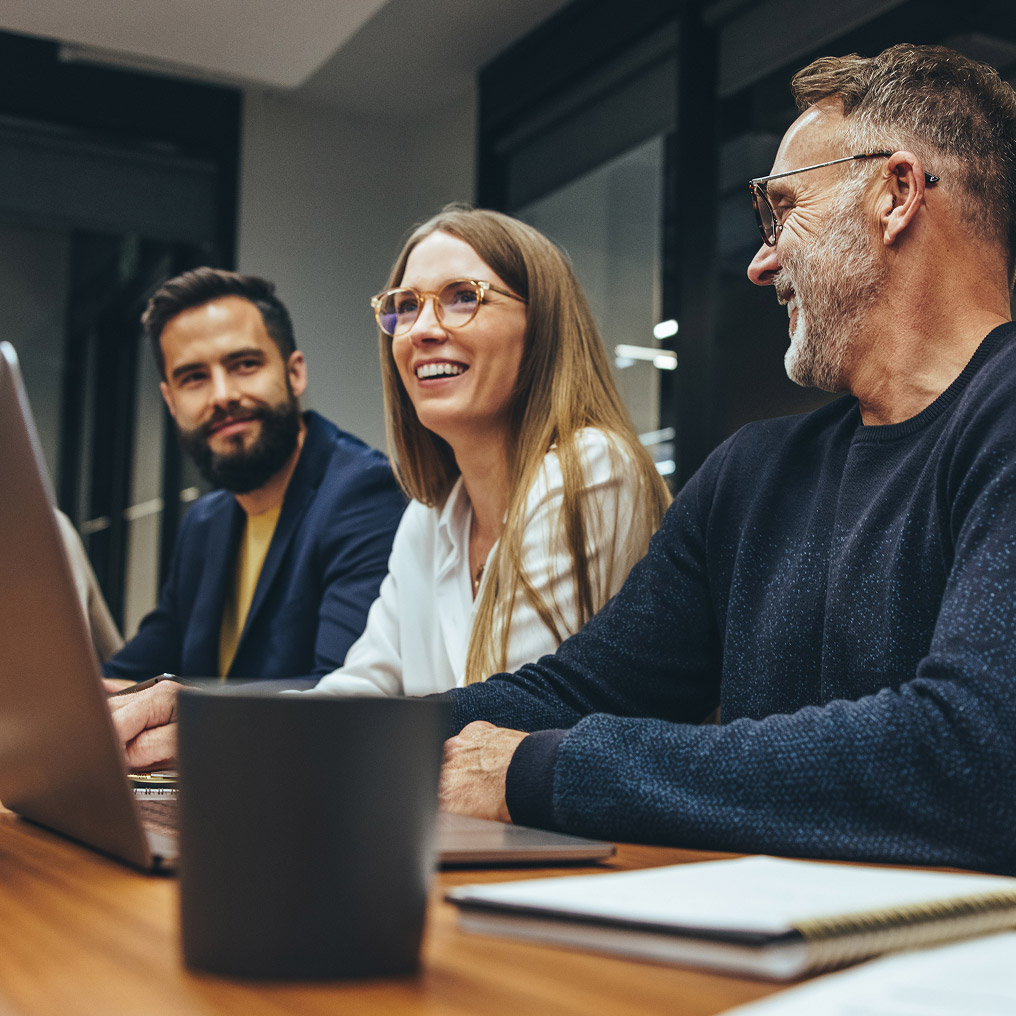 Three colleagues laugh during a meeting